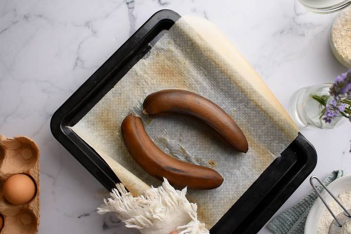 Bananas that have been cooked until dark brown on a baking sheet.