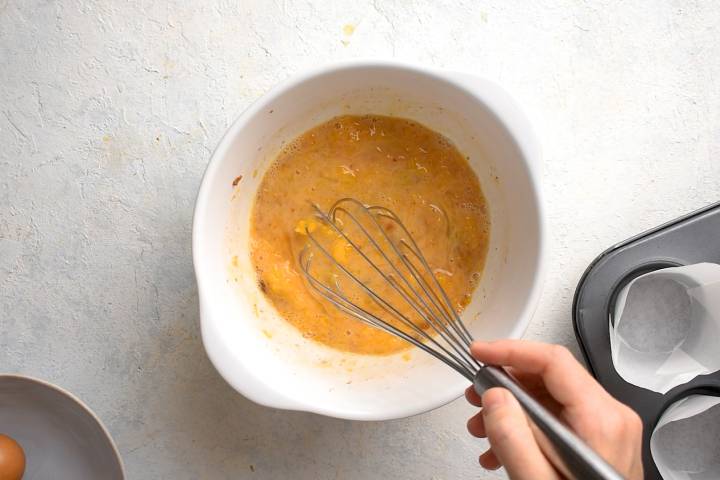 Eggs, canned pumpkin, spices, maple syrup, and milk being whisked in a bowl.