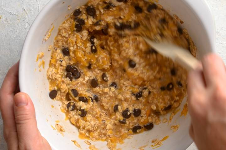 Rolled oats and chocolate chips behind added to canned pumpkin and eggs.