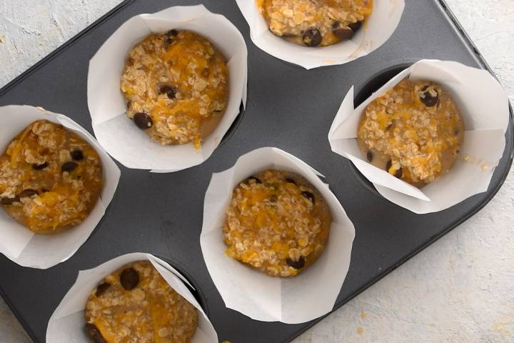 Pumpkin oatmeal muffin mix poured into a muffin tin with parchment liners.