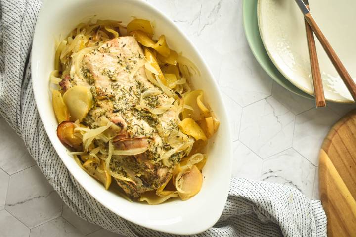 Roasted pork, apples, and onions served in a baking dish.