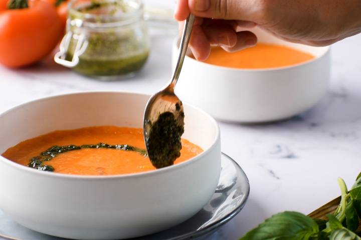 Pesto being drizzled on top of soup. 