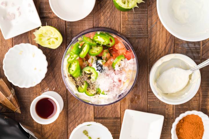 Ingredients for southwestern dressing in a food processor with empty bowls on the side.