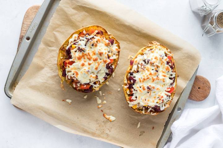 Spaghetti squash burrito bowls with beans and melted cheese on a baking sheet.