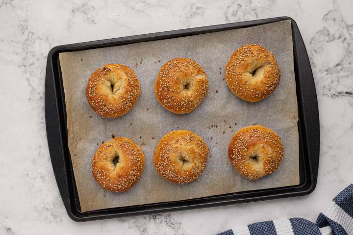 Baked two ingredient sesame seed bagels on a baking sheet.