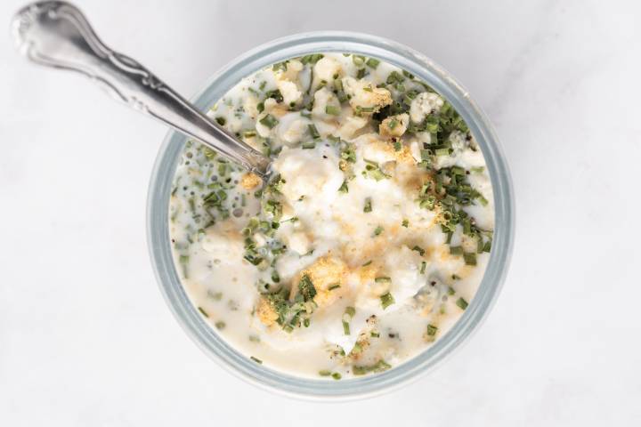 Ingredients for blue cheese salad dressing in a glass bowl with a spoon.