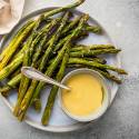 Roasted asparagus on a plate with hollandaise sauce.