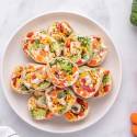 Healthy cream cheese pinwheels with vegetables served on a white plate/