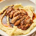 Air fryer turkey breast tenderloin with herbs and sauce on a plate with mashed potatoes.