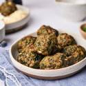 Spinach meatballs made with ground beef served on a plate with spinach and Parmesan cheese on the side.