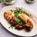 Baked turkey tenderloin sliced on a plate with fresh herbs.