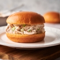 Chicken salad sandwich with shredded chicken, mayonnaise, celery, salt, and pepper on a brioche roll. 