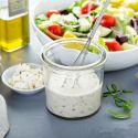 Greek salad dressing in a jar with feta cheese on the side.