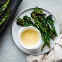 Garlic grilled broccolini served on a plate with fresh lemon and garlic aioli 