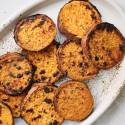 Grilled sweet potatoes with olive oil and spices on a large white plate.