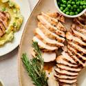 Grilled turkey breast tenderloin served with maple mustard marinade on a plate with peas and rosemary.