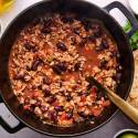 Healthy turkey chili in a soup pot woith ground turkey, kidney beans, peppers, onions, and tomatoes. 