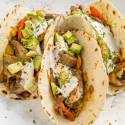 Portobello mushroom fajitas with peppers, onions, mushrooms, guacamole, and sour cream in a warm corn tortilla.