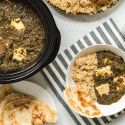 Slow cooker saag paneer on a plate with brown rice and Naan bread with the slow cooker on the side.