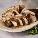 Turkey tenderloin with gravy sliced and served on a plate.