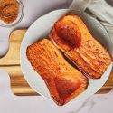 Whole roasted butternut squash hlaves served on a plate with olive oil, salt, pepper, and brown sugar.