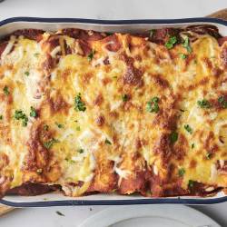 The freshly baked breakfast enchiladas are topped with melted cheese and garnished with fresh parsley. The dish is golden and bubbly from the oven.