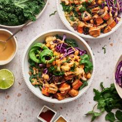 Buddha bowl with kale, chickpea, sweet potatoes, onions, and avocado served with maple tahini dressing.