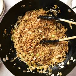 Healthy chow mein with cabbage, noodles, and celery in soy sauce in a wok.