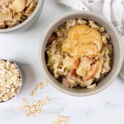 Microwave apple oatmeal with peanut butter and cooked apples in a bowl with cinnamon.