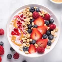 Peanut butter and jelly yogurt bowl with peanut butter, strawberry jelly, peanuts, and fresh fruit.