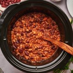 Slow cooker turkey chili with ground turkey, pinto beans, kidney beans, and tomatoes in a slow cooker.