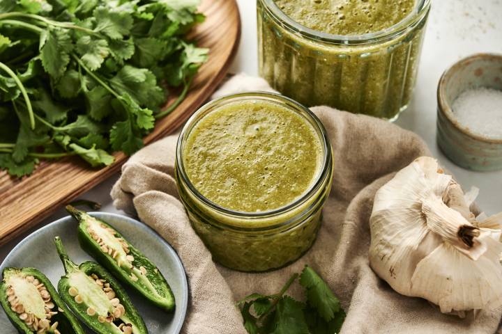 Green enchilada sauce with tomatillos and jalapenos stored in a glass jar.