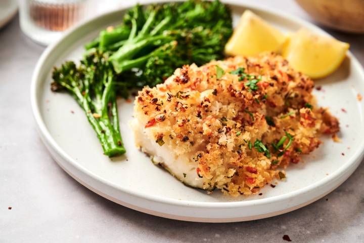 Baked haddock with seafood stuffing served with broccoli and lemon wedges.