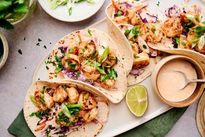 Bang bang shrimp tacos with creamy coleslaw, cilantro, green onions, and crispy shrimp in corn tortillas.