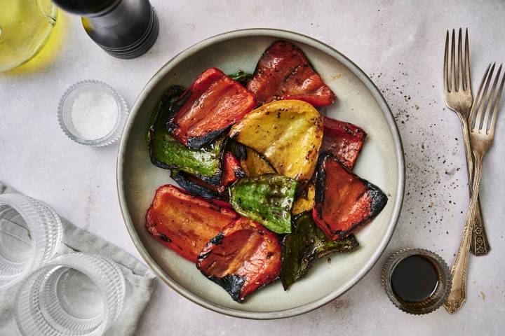 Grilled peppers with red, green, and yellow peppers with balsamic glaze on a plate.