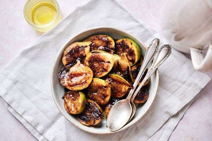 Grilled figs with balsamic glaze served in a bowl with two spoons.