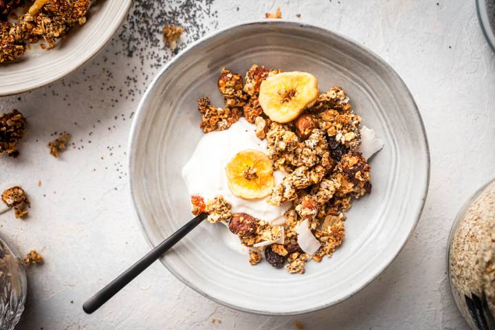 Healthy granola with rolled oats, chia seeds, coconut, nuts, and dried fruit in a bowl with Greek yogurt.