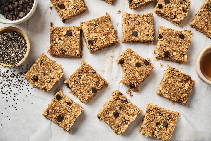 No Bake Oatmeal bars with chocolate chips, chia seeds, flaxseed, and coconut on parchment paper.