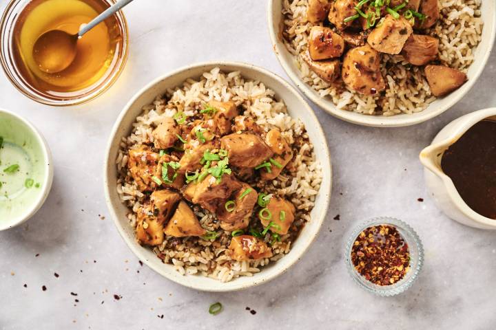 Slow cooker honey garlic chicken with green onions over a bed of brown rice