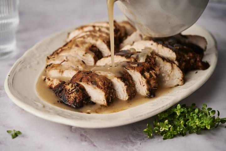 Turkey tenderloin with gravy sliced and served on a plate.