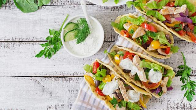 Chicken tacos with fresh vegetables on a gray cutting board for leftovers.