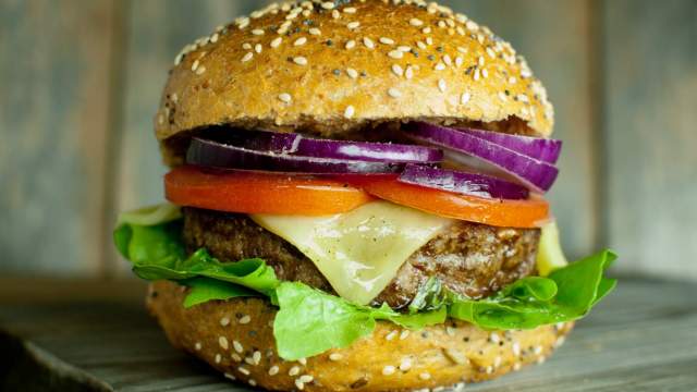 A healthy Beef Ranch burger on a bun with cheese, tomatoes, and onions.