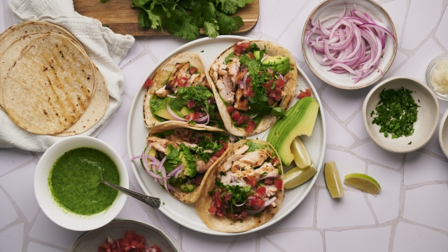 Mexican chicken tacos with tomatoes, onions, tortillas, salsa, and cilantro.