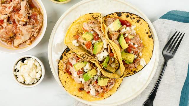 Frozen chicken cooked down to make tinga tacos with tortillas, avocado, and cheese.