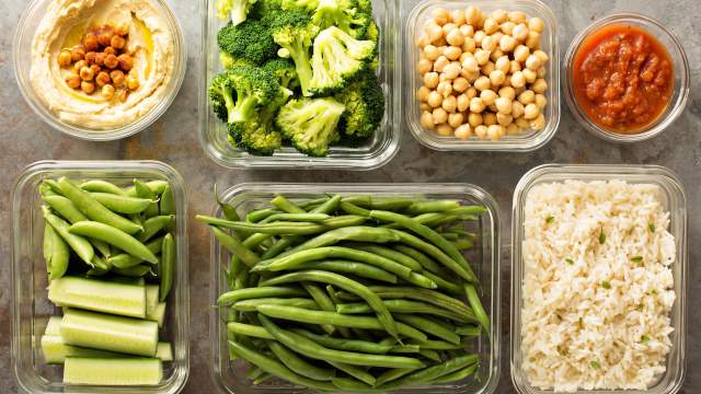 Vegetarian meal planning with containers of hummus, vegetables, chickpeas, and rice.