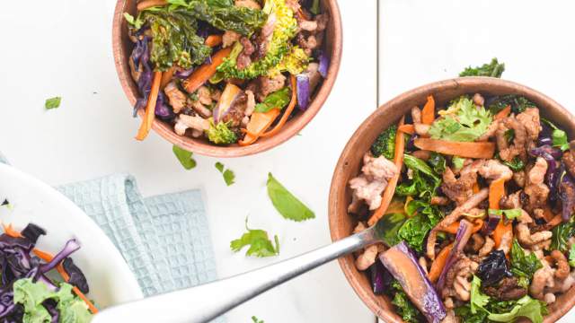 Asian ground turkey stir fry with kale, carrots, broccoli, and soy sauce in two bowls.