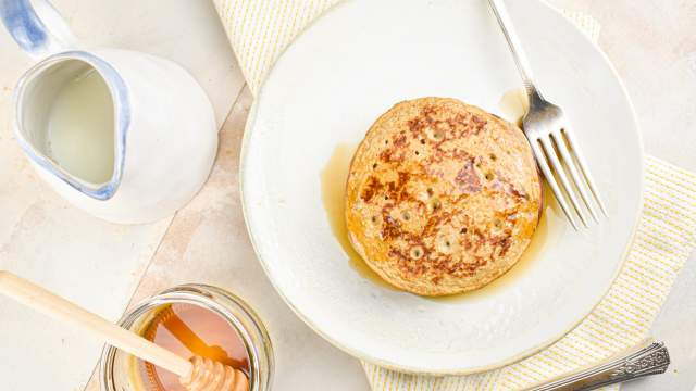 Banana flax pancakes on a plate with syrup on the side.