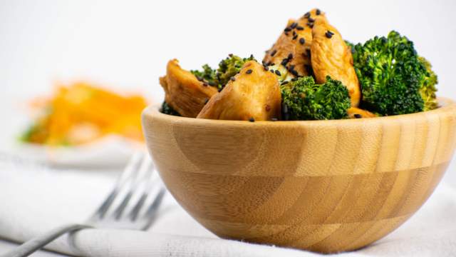 Chicken broccoli stir fry with stir fry sauce in a wooden bowl with sesame seeds.