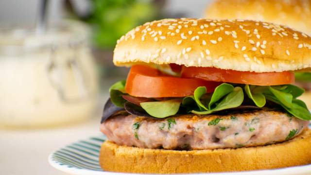 Chicken caesar burger with lettuce and tomato on a bun.