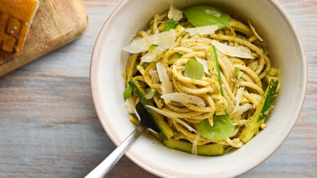 Creamy pesto pasta with zucchini, basil pesto, and Parmesan cheese in a ceramic bowl.